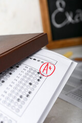 Book and checked answer sheet forms on table, closeup