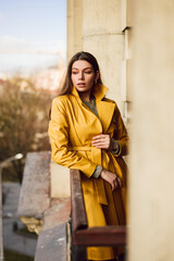 Young woman wearing stylish trendy yellow leather trench coat. Casual outfit