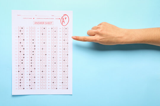 Female hand with answer sheet form on color background