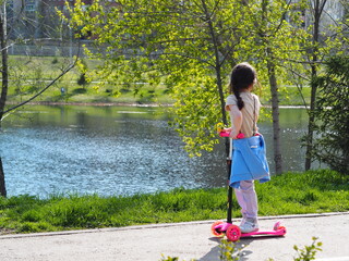 Spring warm day off.Children walk and ride scooters in a city park in nature. © Татьяна Пинкасевич
