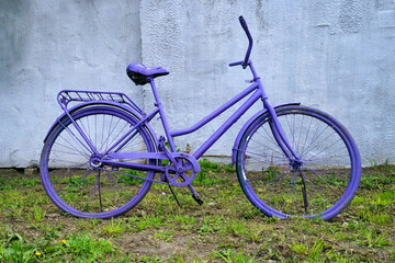 Fototapeta na wymiar Purple painted dilapidated bicycle on the wall background