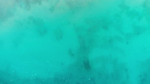 A beautiful video of a drone flying over the blue water of the ocean with the smooth surface of the water glittering from the sun in the Seychelles