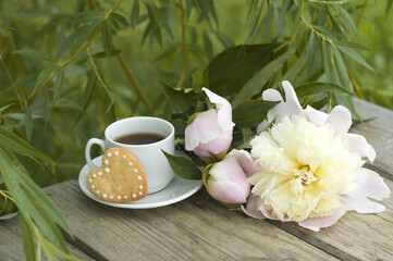 beautiful pink peonies, a cup of coffee, heart-shaped cookies. romantic breakfast. summer vacation.