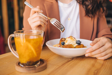 smiling beautiful woman in cafe eating cake with ice cream and blueberries