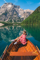 woman sitting in big brown boat at lago di braies lake in Italy