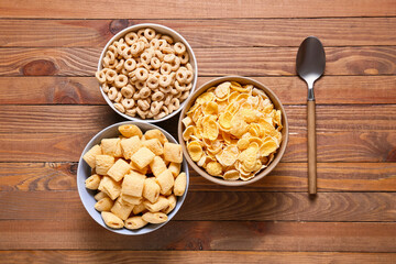Bowls of different cereals on wooden background