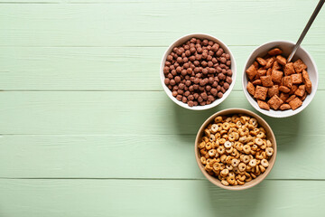 Bowls of different cereals on color wooden background