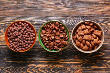 Bowls of different cereals on wooden background