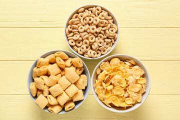 Bowls of different cereals on color wooden background