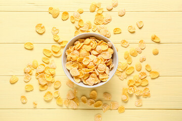 Bowl with tasty corn flakes on color wooden background
