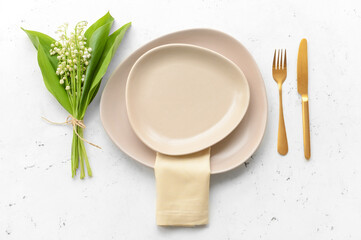 Beautiful table setting with lily-of-the-valley flowers on light background