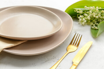 Beautiful table setting with lily-of-the-valley flowers on light background