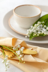 Beautiful table setting with lily-of-the-valley flowers on light background