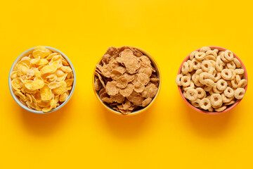 Bowls with different cereals on color background