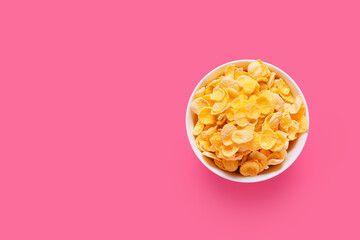 Bowl with tasty corn flakes on color background