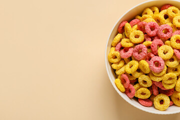 Bowl with cereal rings on color background, closeup