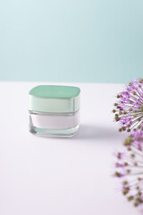 beauty cosmetic cream in a white container, with flowers on a white-blue background