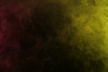 Obraz na płótnie Canvas Artificial magic smoke in red-yellow light on black background