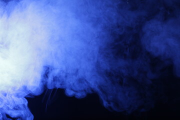 Artificial smoke in blue light on black background