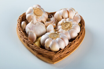 Garlic Cloves and Bulb in Heart Basket on White Background