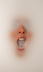 Woman underwater with her mouth open and filled with milk. Milk surrounds her face and covers her eyes. She appears to be screaming under the water.