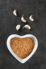 Garlic Cloves and Bulb in Heart Bowl with Dark Background