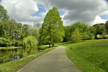 Chemin en asphalte entre l'étang et la pelouse au jardin Jean Sobieski à Laeken