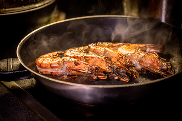 Grilled prawn in a frying pan on a dark background. Seafood appetizer.