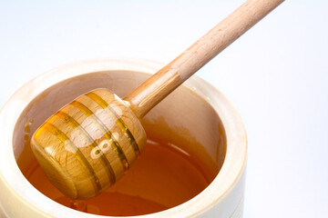 Honey in cup,spoon wood on white background.