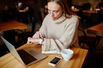 Scared woman watching time in cafe