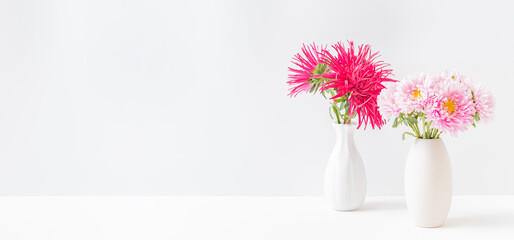 Pink and red flowers in a vase on a light background at home interior. Modern interior design