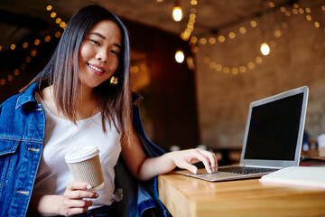 Smiling Asian woman typing on laptop