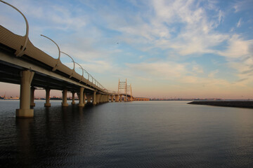 View of the cable-stayed bridge and the autobahn supports over the water  at sunset 