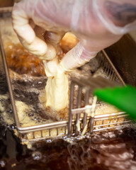 A chef drops a piece of battered fish into a hot oil fryer.