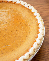Close up of crust edge of a pumpkin pie cropped with half of pie showing.