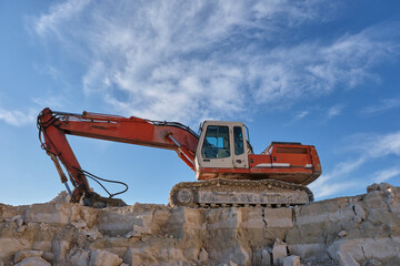 Excavator stands on the background of a stone quarry.