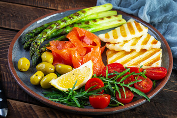 Salad with asparagus, grilled halloumi cheese, salmon fillet, tomatoes, arugula and green olives