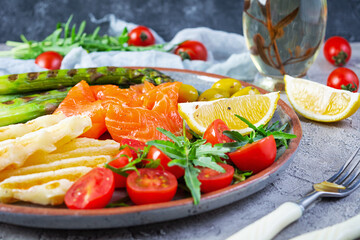 Salad with asparagus, grilled halloumi cheese, salmon fillet, tomatoes, arugula and green olives