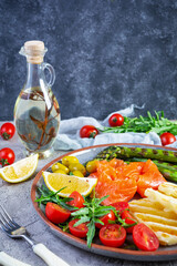 Salad with asparagus, grilled halloumi cheese, salmon fillet, tomatoes, arugula and green olives