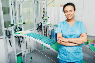 Portrait of a physiotherapist woman wearing a medical uniform standing at a rehabilitation center with arms crossed. Staff of rehab clinic