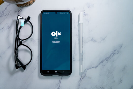 flatlay shot of mobile phone showing the logo of olx india's largest second hand reseller marketplace similar to ebay and craigslist in India asia