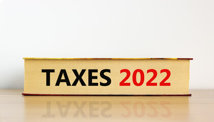 Obraz premium Taxes planning 2022 new year symbol. Concept words 'Taxes 2022' on book on wooden table. Beautiful white background. Business, taxes planning 2022 new year concept.