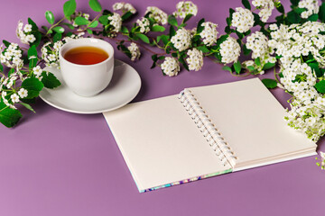 Cozy spring purple background with a mug of tea. Floral composition with space for text
