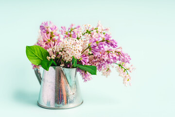 A beautiful spring bouquet of lilacs in a vase on a light blue background, a beautiful floral composition. Minimalistic background