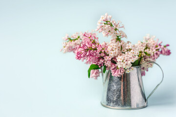A beautiful spring bouquet of lilacs in a vase on a light blue background, a beautiful floral composition. Minimalistic background