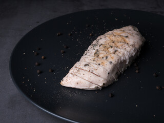 Sous-vide grilled chicken with herbs in cast-iron skillet on black plate. Grey background with copy space