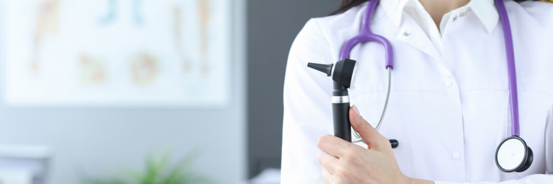 Doctor In Protective Mask Holds An Otoscope In His Hands