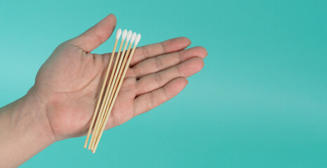 Cotton sticks for swab in hand on mint green or Tiffany Blue background.covid-19 concept