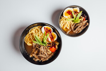 Two fresh and tasty Japanese ramen soup with beef, egg, noodles and sprout on bright  background...