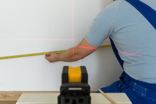 a skilled person marks a point on the wall marked with an electronic laser